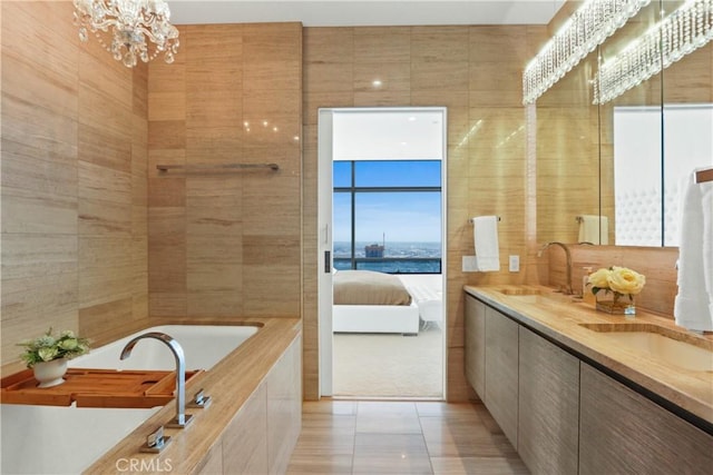 bathroom with vanity, a water view, tile patterned flooring, tile walls, and a notable chandelier