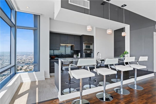 kitchen featuring decorative backsplash, dark hardwood / wood-style floors, a towering ceiling, decorative light fixtures, and stainless steel appliances