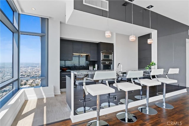 900 W Olympic Blvd Unit 42A, Los Angeles, CA 90015 - kitchen featuring appliances with stainless steel finishes, a high ceiling, dark cabinetry, wood finished floors, and hanging light fixtures