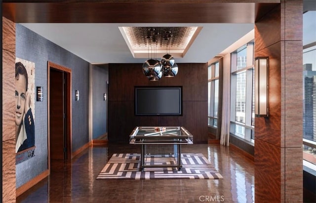 interior space with elevator, a raised ceiling, and a notable chandelier