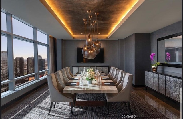 dining space with dark hardwood / wood-style flooring, expansive windows, and a raised ceiling