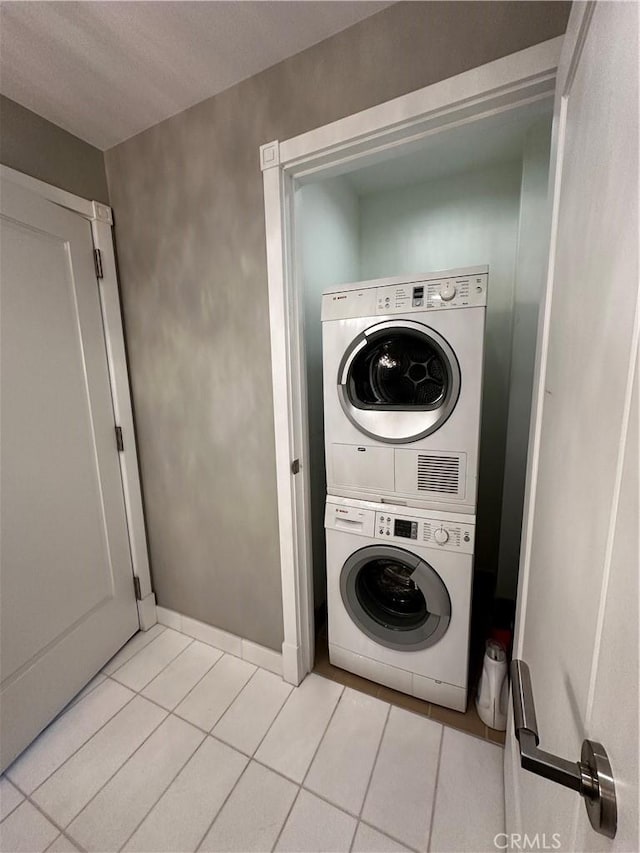 laundry area featuring stacked washer / dryer and light tile patterned flooring