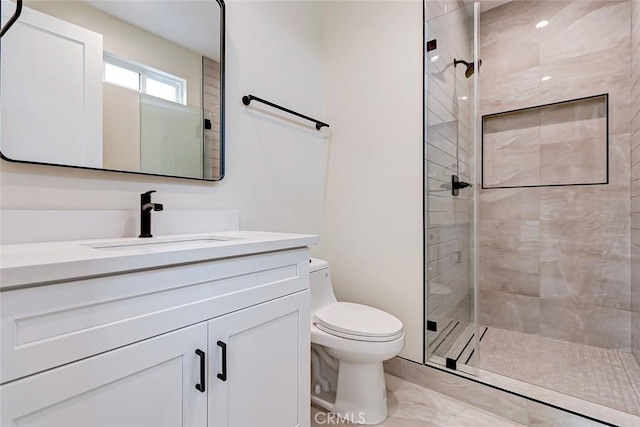 bathroom featuring vanity, toilet, and a shower with door