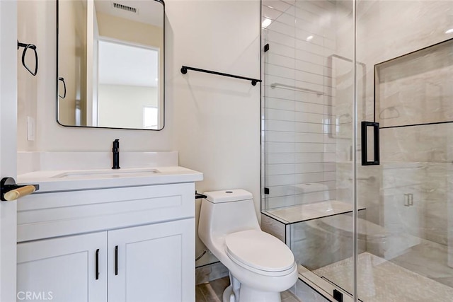 bathroom featuring vanity, a shower with shower door, and toilet