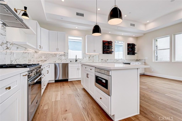 kitchen with white cabinetry, pendant lighting, extractor fan, and appliances with stainless steel finishes