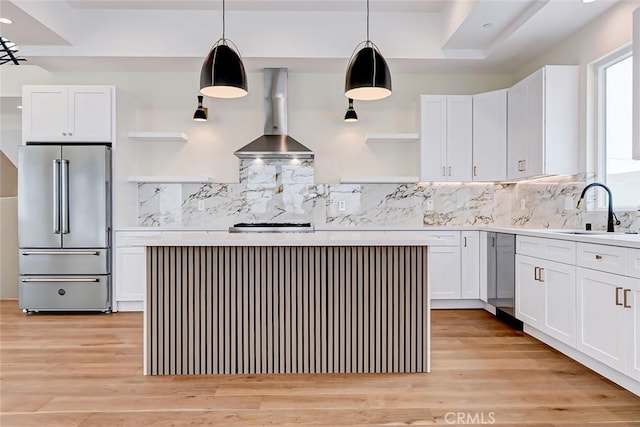 kitchen with white cabinetry, high end refrigerator, pendant lighting, and wall chimney range hood