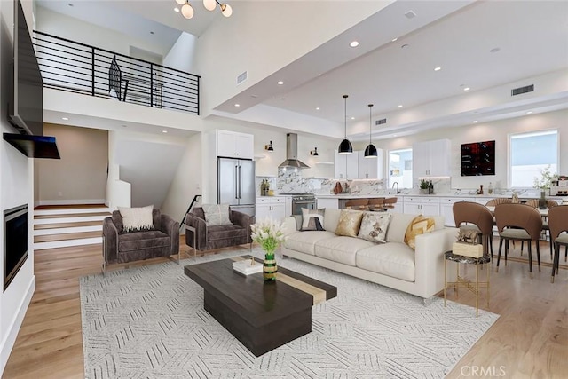 living room with light hardwood / wood-style flooring, a high ceiling, and sink