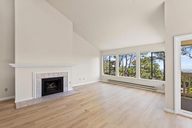 unfurnished living room with high vaulted ceiling, baseboard heating, a tiled fireplace, and light wood-type flooring