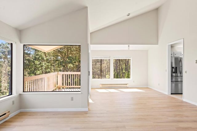 unfurnished room featuring baseboard heating, light hardwood / wood-style floors, and plenty of natural light