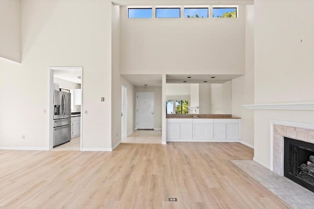 unfurnished living room featuring a high ceiling, a fireplace, and light hardwood / wood-style flooring