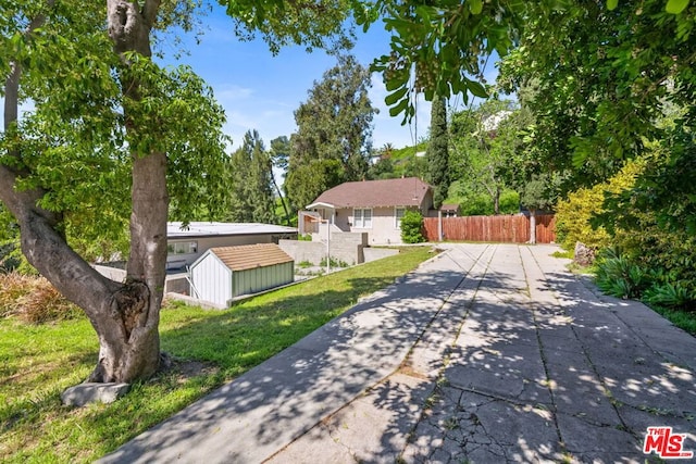 single story home with a front yard, a storage unit, and a patio area