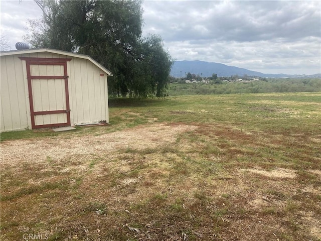 view of yard with a mountain view, a rural view, and a storage shed