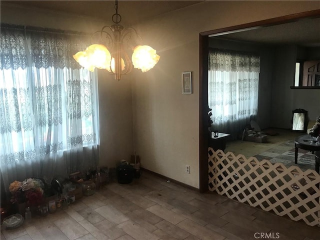 dining room featuring a healthy amount of sunlight, wood-type flooring, and a chandelier