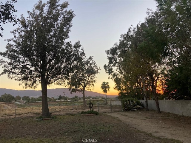 yard at dusk with a mountain view and a rural view