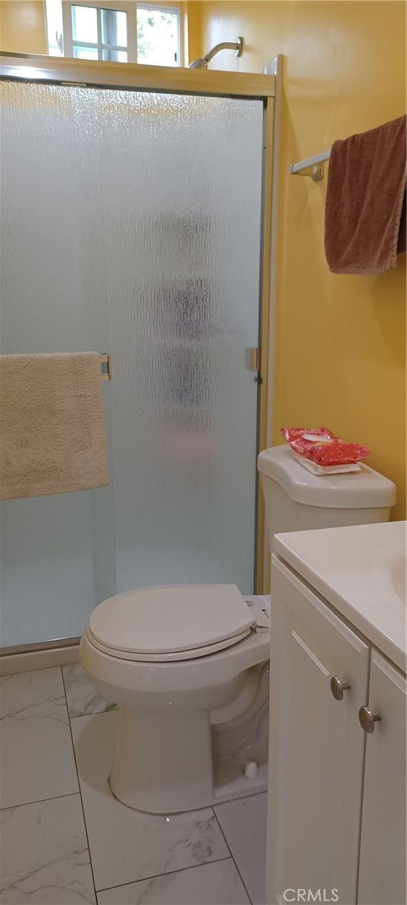 bathroom featuring vanity, toilet, and an enclosed shower