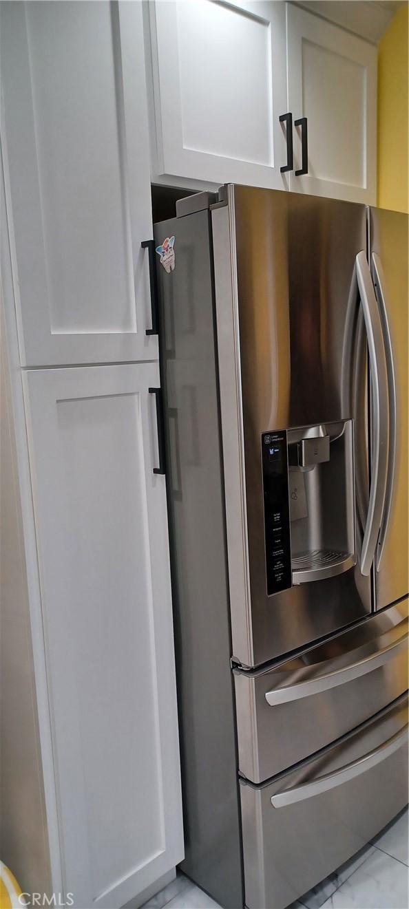 kitchen with stainless steel fridge and white cabinetry