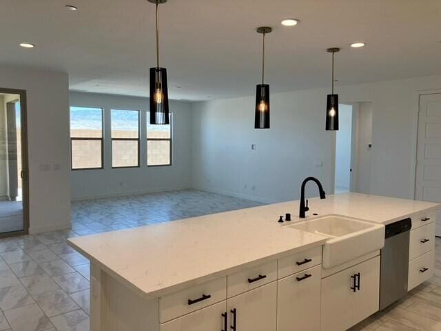 kitchen with white cabinetry, dishwasher, sink, hanging light fixtures, and an island with sink