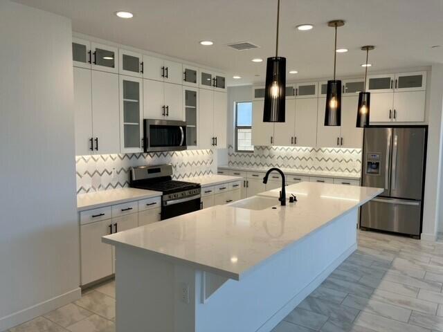 kitchen featuring hanging light fixtures, a center island with sink, stainless steel appliances, and sink