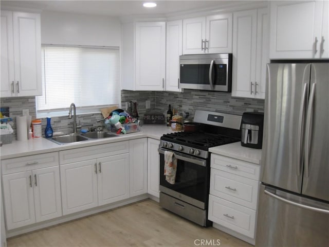 kitchen featuring stainless steel appliances, sink, white cabinets, and decorative backsplash