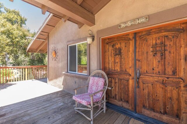 view of exterior entry featuring covered porch and a deck