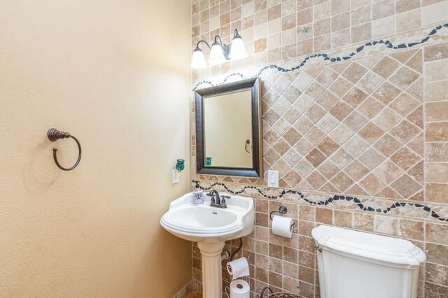 bathroom featuring toilet and tile walls