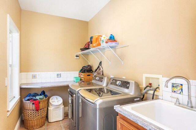 washroom with cabinets, washing machine and clothes dryer, sink, and light tile patterned floors