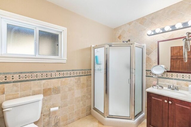 bathroom with tile walls, vanity, toilet, and walk in shower