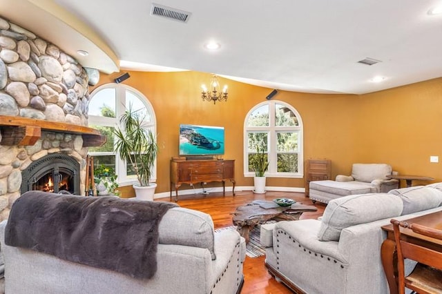 living room featuring light hardwood / wood-style floors, a healthy amount of sunlight, a chandelier, and a fireplace