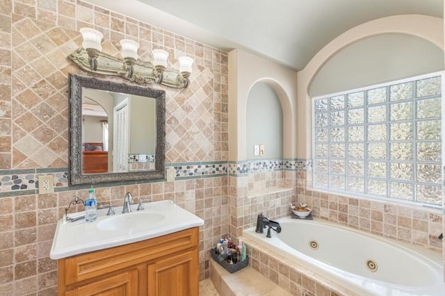 bathroom with vanity, tiled bath, and tile walls