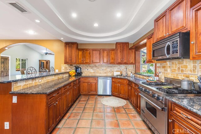 kitchen featuring sink, appliances with stainless steel finishes, kitchen peninsula, ceiling fan, and decorative backsplash