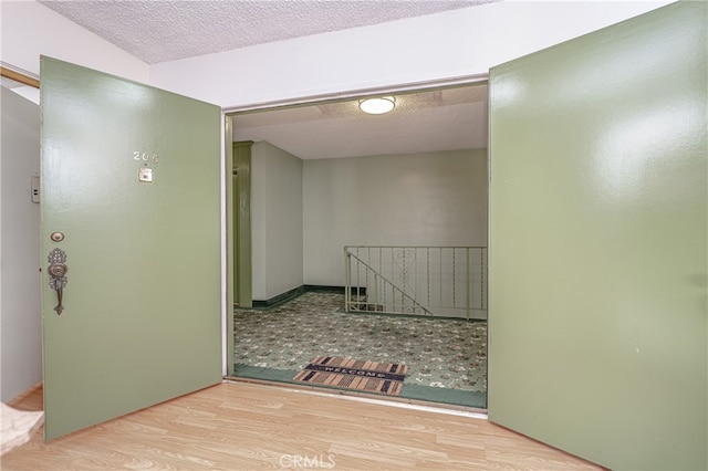 hall featuring a textured ceiling and light tile flooring