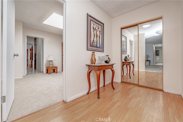 hallway featuring a skylight, light colored carpet, and a textured ceiling