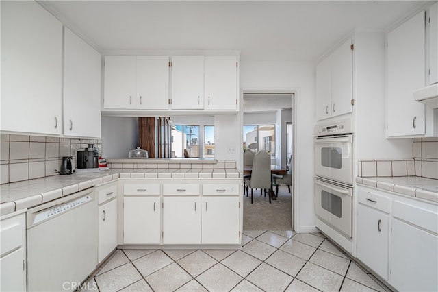 kitchen with white appliances, tile counters, white cabinetry, and light tile floors