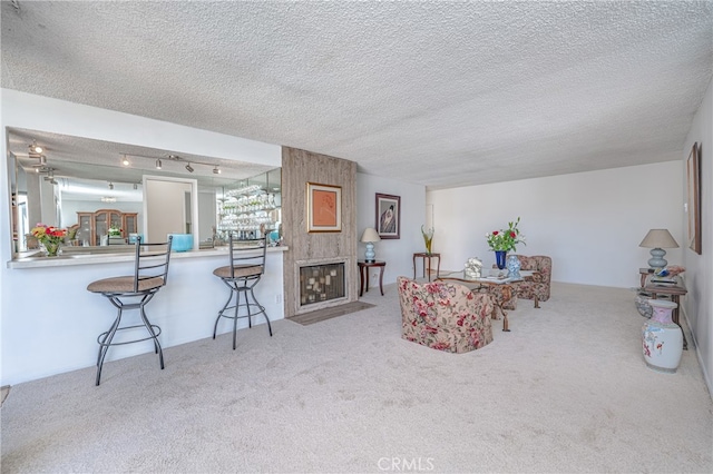 living room featuring a textured ceiling, carpet floors, and a large fireplace