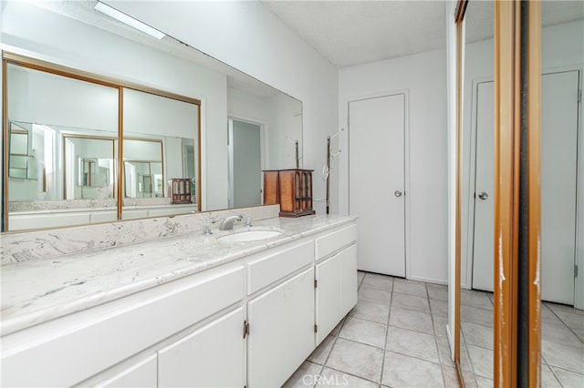 bathroom with tile flooring, vanity, and a textured ceiling