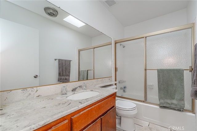 full bathroom with tile flooring, vanity, toilet, and bath / shower combo with glass door