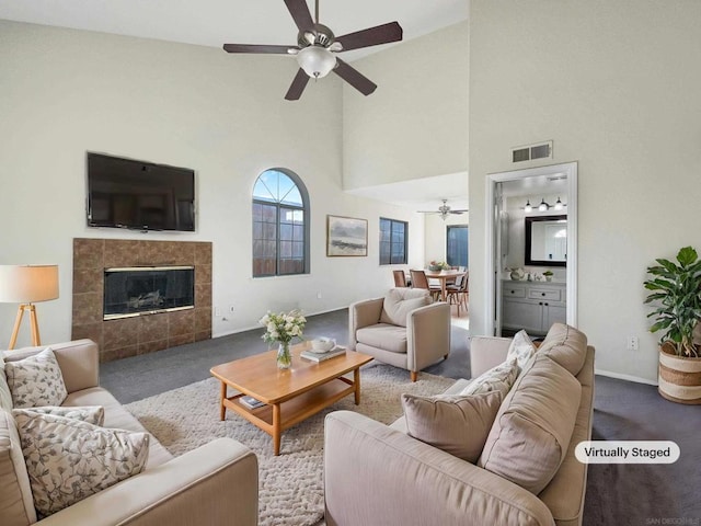 living room featuring carpet flooring, high vaulted ceiling, a tile fireplace, and ceiling fan