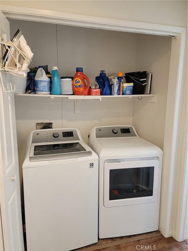 clothes washing area featuring washer and clothes dryer and wood-type flooring