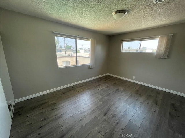 unfurnished room featuring dark hardwood / wood-style flooring and a textured ceiling