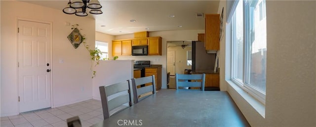 kitchen with black appliances, light tile patterned floors, and ceiling fan with notable chandelier