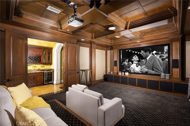 carpeted cinema room featuring beverage cooler, coffered ceiling, beamed ceiling, indoor bar, and ornamental molding