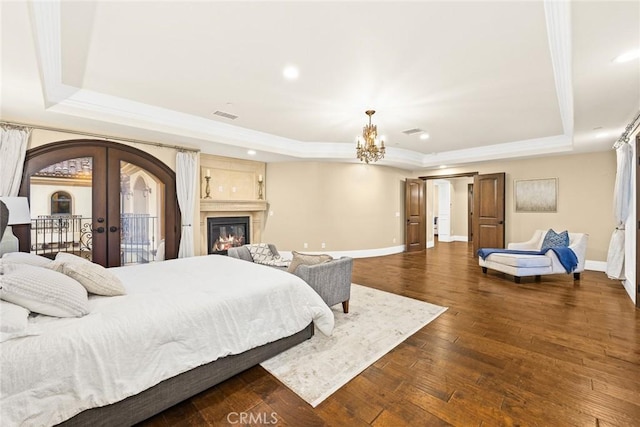 bedroom with a tray ceiling, dark hardwood / wood-style flooring, french doors, and access to exterior