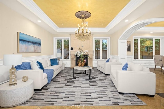 tiled living room featuring a tray ceiling, crown molding, and a chandelier