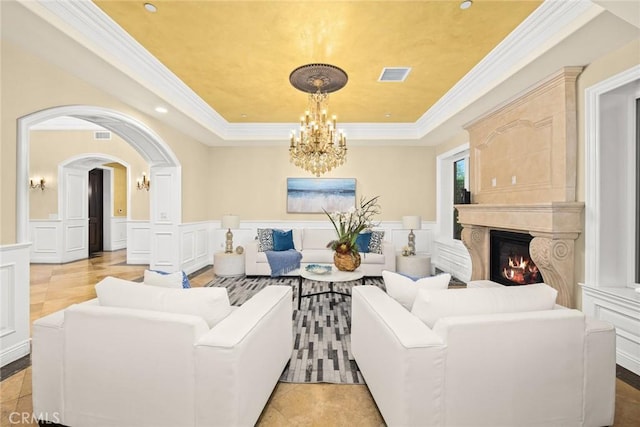 living room with a raised ceiling, a high end fireplace, and ornamental molding