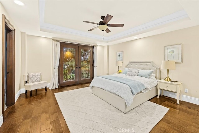 bedroom featuring ceiling fan, dark wood-type flooring, and a tray ceiling