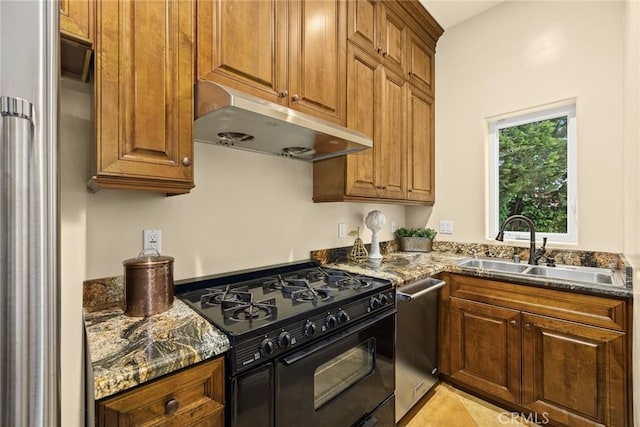 kitchen with stainless steel appliances, dark stone counters, and sink