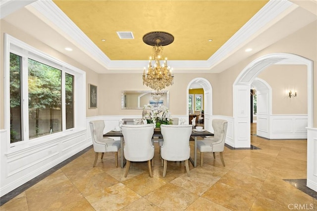 dining space featuring a tray ceiling, crown molding, and a notable chandelier