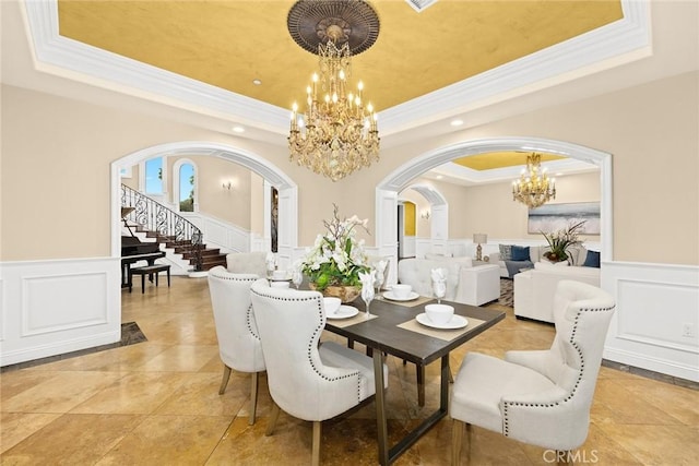 tiled dining area featuring a raised ceiling, a chandelier, and ornamental molding