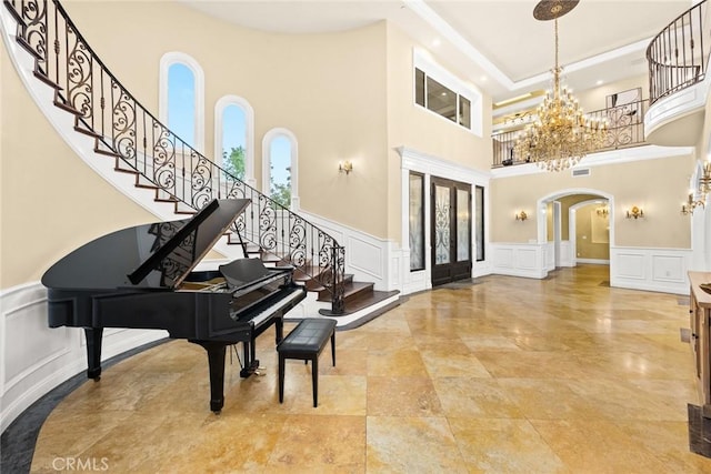 foyer entrance featuring french doors, a towering ceiling, and an inviting chandelier