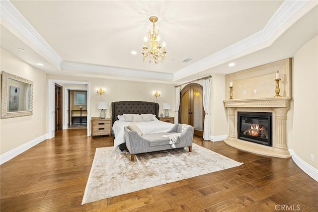 bedroom featuring a chandelier, dark hardwood / wood-style flooring, a tray ceiling, and crown molding